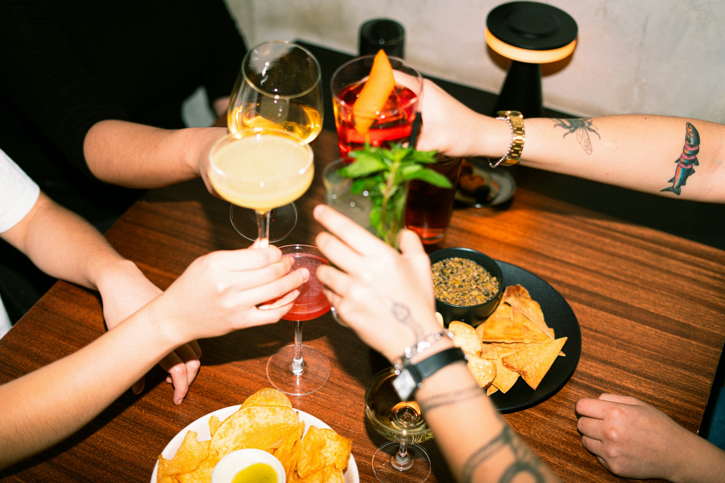 Friends toasting with cocktails and snacks around a table